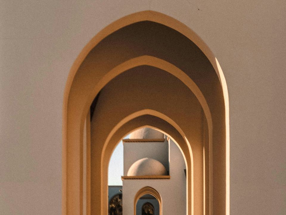 Layered stone arches of a mosque courtyard in warm evening light